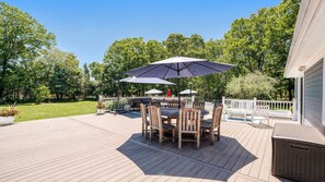A wooden deck with outdoor furniture, including a table and chairs, and umbrellas providing shade.