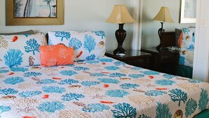 A bedroom with a bed, a ceiling fan, a nightstand, two lamps, a framed picture, and a mirror. - Serene is spending a day in this condo (Rockport)