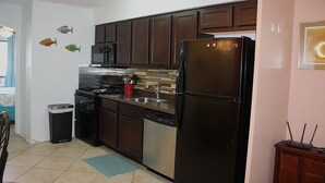A kitchen with dark wooden cabinets, stainless steel appliances, a dishwasher, and a trash can. - Serene is spending a day in this condo (Rockport)