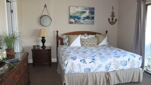 Une chambre à coucher avec un lit, une table de chevet, une lampe, un miroir et un tableau.