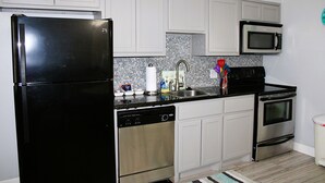 A kitchen with white cabinets, a black refrigerator, a dishwasher, a microwave, and an oven. - Modern retreat on the water (Rockport)