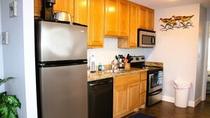 A kitchen with wooden cabinets, stainless steel appliances, and a microwave. - Corner condo with bay window overlooking pool (Rockport)