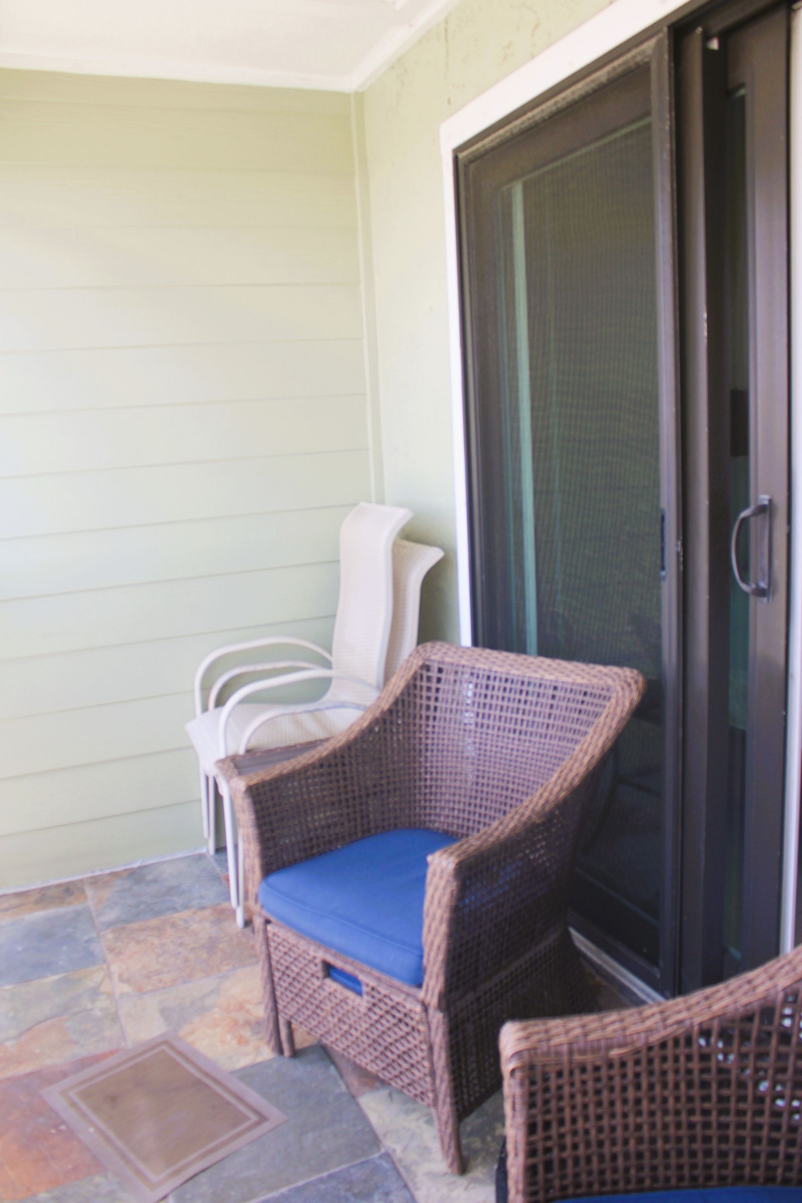 A patio area with wicker furniture and a sliding glass door.