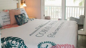 Une chambre à coucher avec un lit, un ventilateur de plafond, une table de chevet, une lampe et une vue sur l’extérieur.