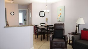 Un salon comprenant un coin repas, un fauteuil en cuir, un canapé, une lampe et un tableau accroché au mur.