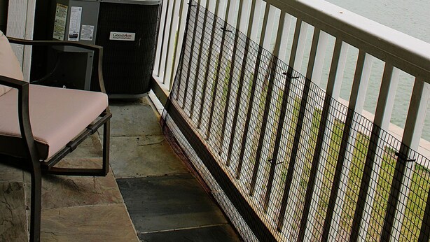 Un balcon donnant sur une étendue d’eau, une poubelle et une chaise.