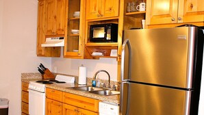 Eine Küche mit Holzausstattung, Edelstahlgeräten und gefliestem Boden.