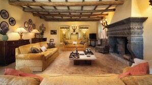 Una sala de estar acogedora con chimenea, vigas de madera en el techo y un conjunto de sofás cómodo.