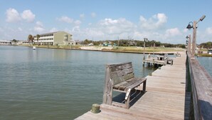 Un muelle de madera que se adentra en aguas tranquilas, con un banco y un farol.