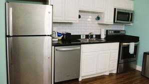 A kitchen with white cabinets, stainless steel appliances, a dishwasher, a microwave, and a stove. - Second floor condo with canal view (Rockport)