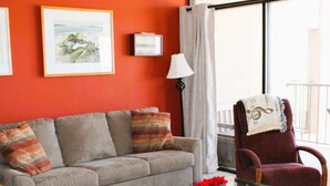 Una sala de estar con sofá, sillón, mesa de centro y ventilador de techo.