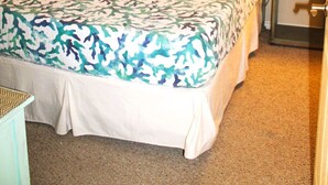 Una cama con colcha estampada, dos mesitas de noche con lámparas y una mesita auxiliar con cajón.