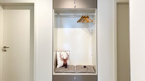 A walk-in closet with a hanging rod, a padded bench, and a door with a key lock. - Gemütliche & Luxuriöse Ferienwohnung in Top-lage (Höchenschwand)