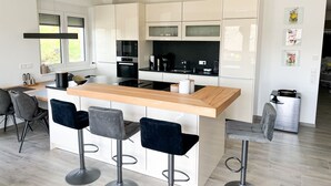 A modern kitchen with white cabinets, a wooden island, and bar stools. - Gemütliche & Luxuriöse Ferienwohnung in Top-lage (Höchenschwand)
