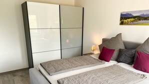 A modern bedroom with a bed, a wardrobe, and a nightstand. - Gemütliche & Luxuriöse Ferienwohnung in Top-lage (Höchenschwand)