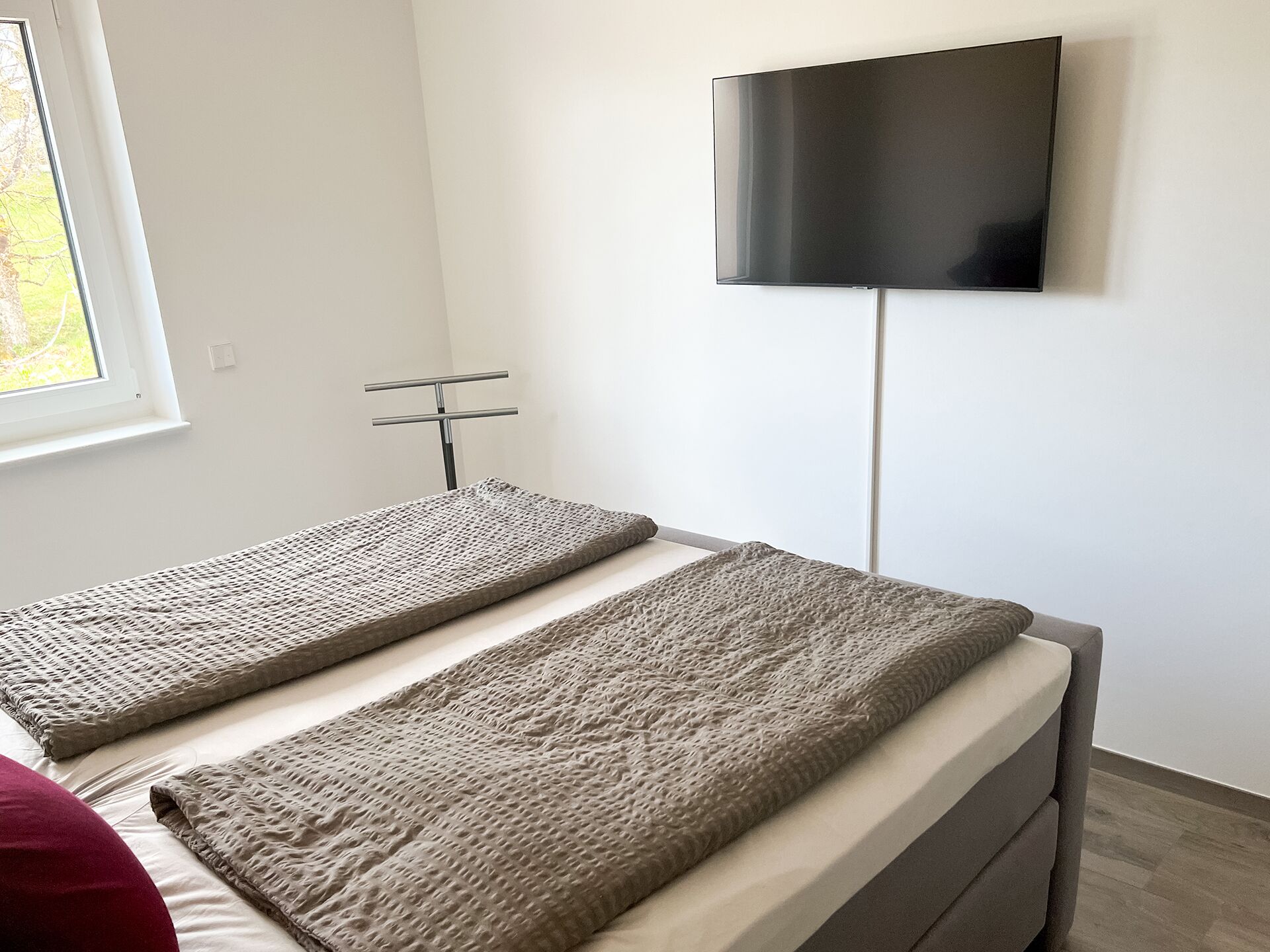 Una camera da letto con un letto, una TV a parete e una finestra.
