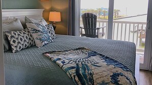 A bedroom with a bed, a ceiling fan, a window with a view, and a chair. - Fantastic water view from comfortable cozy condo (Rockport)