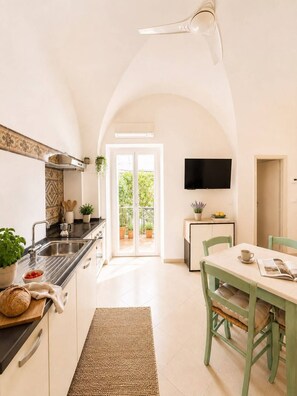 A kitchen with a built-in stove, a sink, and a dining area with a table and chairs. - Old Virginia house, charm with garden and sea (Cervo)