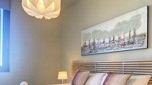 A neatly made bed with rolled towels, a headboard with horizontal slats, a wall-mounted painting of trees, and a hanging light fixture. - Modern, large terrace, pool and BBQ (Mar de Cristal)