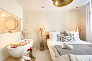 Une chambre à coucher moderne avec un grand lit, une baignoire avec des bougies et un miroir au mur.