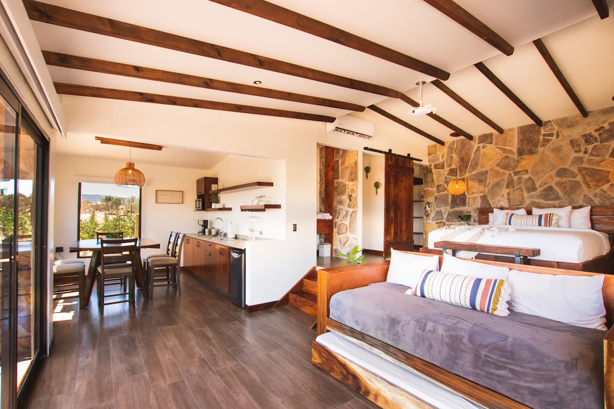 Une pièce spacieuse avec un grand lit, un plafond en bois et un mur en pierre.