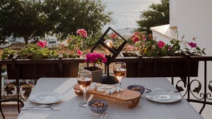 A table set for two with wine glasses, plates, and a small bowl of nuts, overlooking a scenic view of the sea and mountains. - Turgutreis Apart Otel (Bodrum)