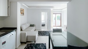 A modern, well-lit room with a sofa, a dining table, and a kitchen area. - Turgutreis Apart Otel (Bodrum)