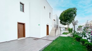 A modern building with a flat roof, a staircase leading to the entrance, and a well-maintained lawn. - Turgutreis Apart Otel (Bodrum)