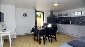 Et lille køkken med spisebord, stole, en radiator og et fjernsyn ophængt på væggen.