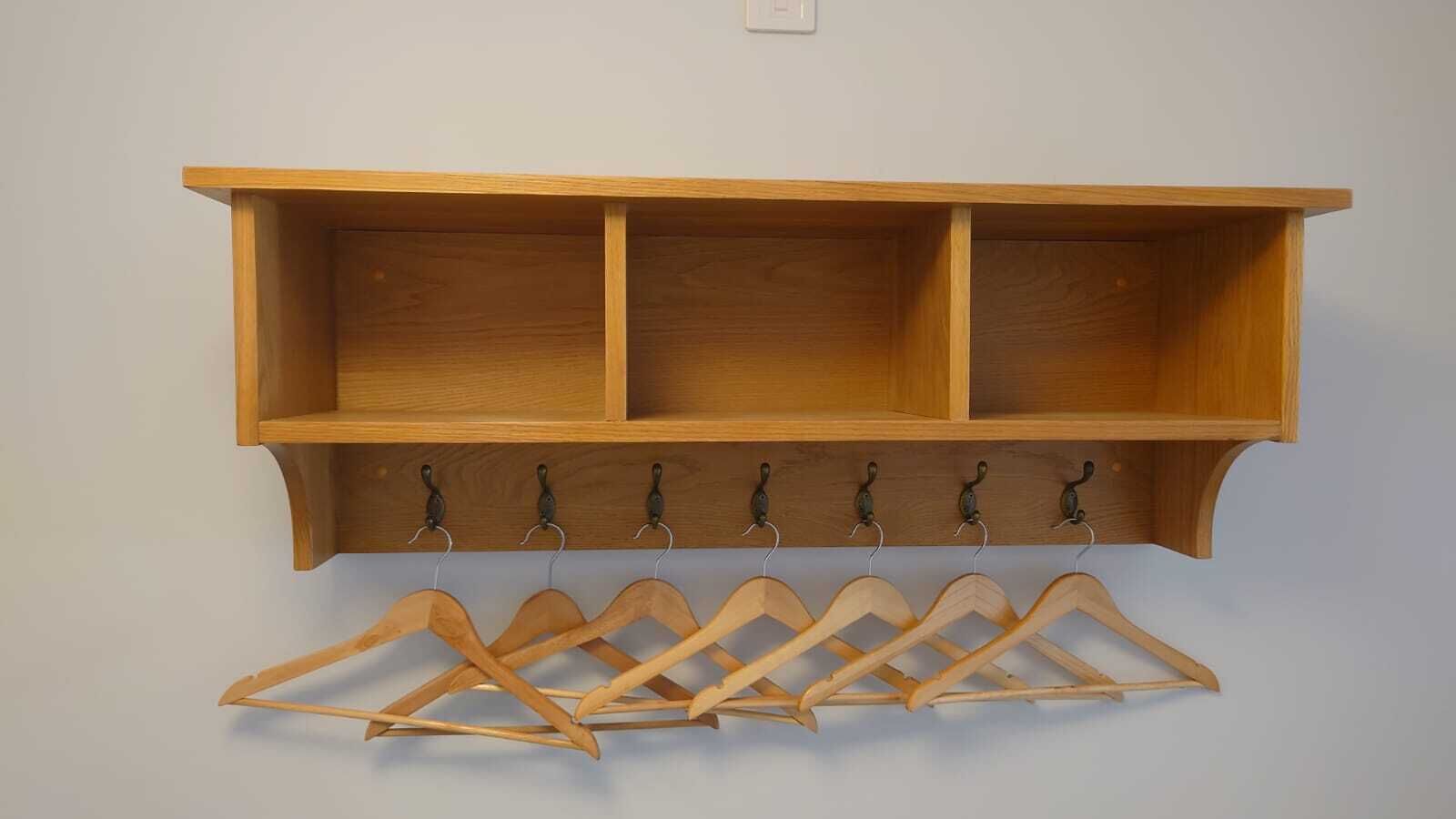 A wooden coat rack with multiple hooks and a wooden shelf above it.