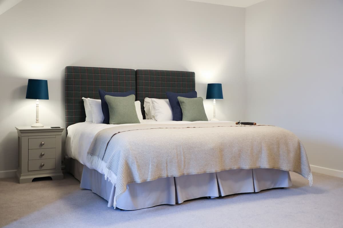 A neatly arranged bedroom with a bed, two bedside tables, and lamps.