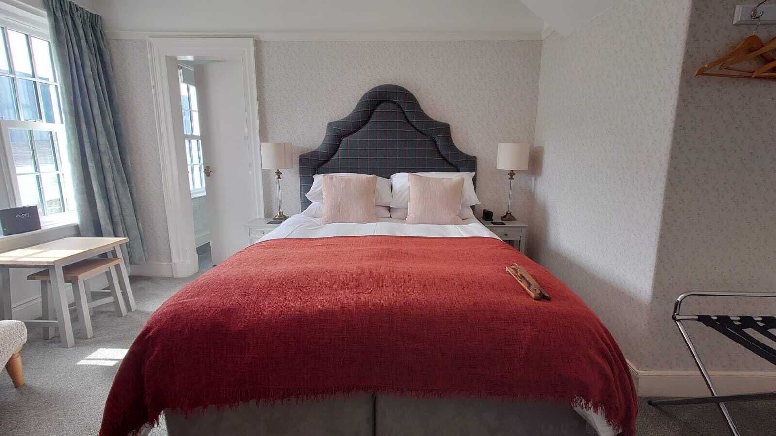 A neatly arranged hotel room with a bed, bedside tables, a desk, and a chair.