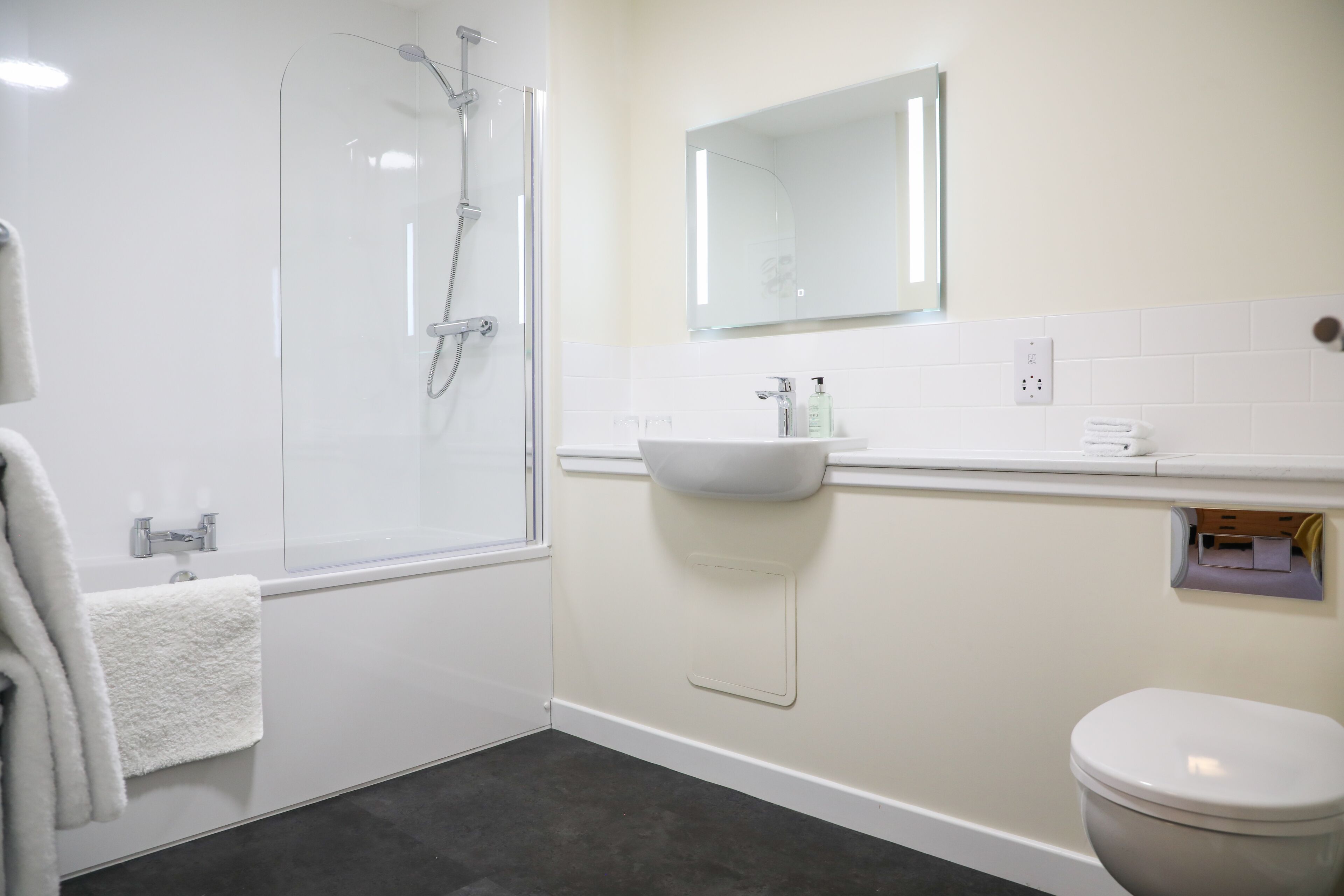 A bathroom with a glass shower enclosure, a white sink, a mirror above the sink, and a toilet.