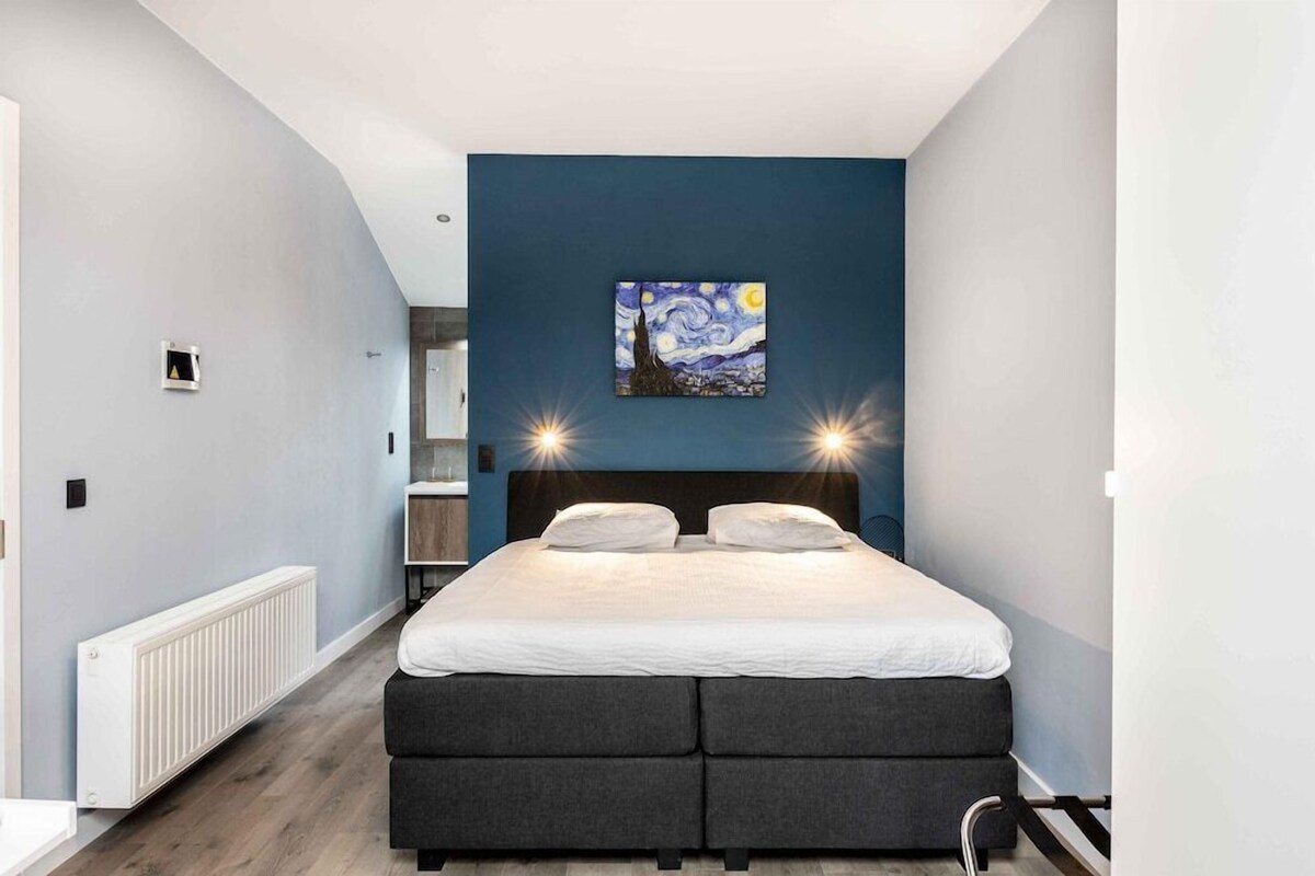 Un dormitorio con cama, un cuadro en la pared y un radiador.