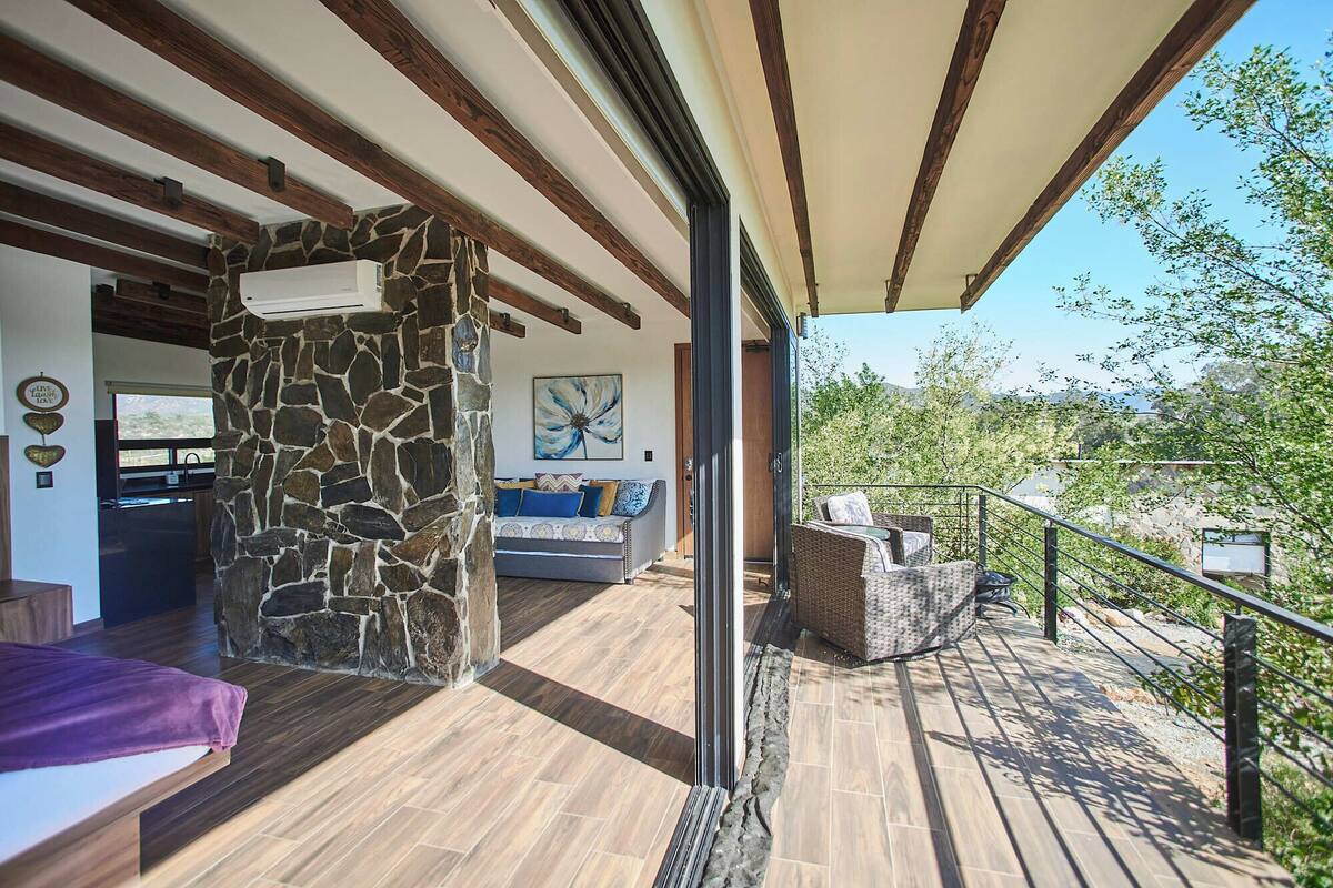 A spacious balcony with a stone wall, a sofa, and a dining area.