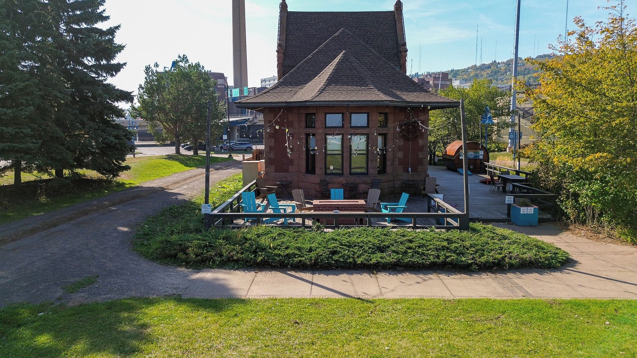 A small brick building with a sloped roof, surrounded by a wooden deck with outdoor seating.