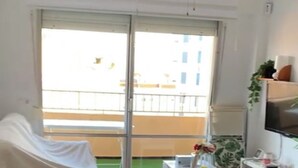 Ein Hotelzimmer mit Bett, Schreibtisch, Stuhl, Fernseher und einem Balkon mit Blick auf Gebäude.