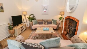 Ein gemütliches Wohnzimmer mit einer Sofagarnitur, einem Couchtisch, einem Kamin und einem Fernseher.