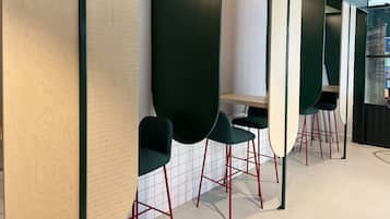 Un interior moderno con una larga encimera, sillas verdes y patas de metal rojas.