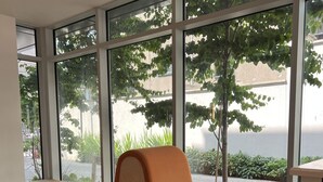 Una habitación moderna con ventanas amplias, un banco acolchado y asientos anaranjados.