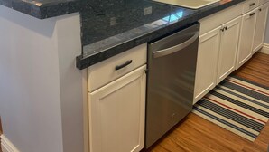 Una cocina moderna con encimera de granito, electrodomésticos de acero inoxidable y un amplio ventanal con vistas al verdor.