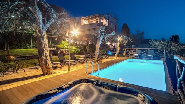 Área de hidromassagem com piscina, espreguiçadeiras e um edifício ao fundo.