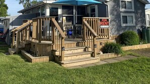 Una casa de dos pisos con un balcón de madera y un cartel de 'For Rent'.