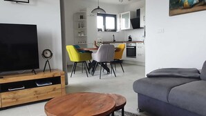 Una sala de estar moderna con un televisor de pantalla plana, un mueble de madera para entretenimiento, un sofá gris y una mesa de centro.