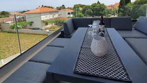 Terraza en la azotea con una mesa dispuesta para comer, con vistas a una zona residencial con casas y árboles.