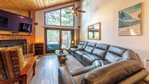 A modern living room with a leather sofa, a wooden coffee table, and a fireplace. - Townhouse at the Woodlands 235 (Mammoth Lakes)