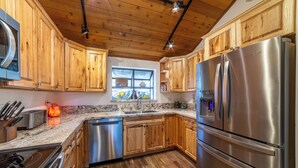 A modern kitchen with wooden cabinets, stainless steel appliances, and a granite countertop. - Townhouse at the Woodlands 235 (Mammoth Lakes)