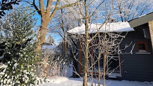 A house with a snow-covered roof and a large tree in front.