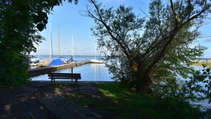 A wooden dock extending into calm water with sailboats moored at the end.