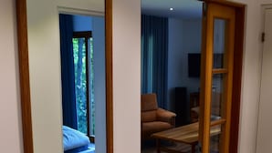 A room with a bed, a wooden table, and a mirror on the wall.